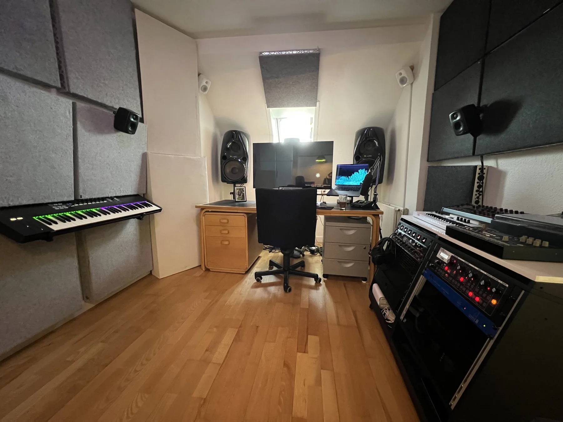 Wide overview of Julius Sylvest's Dolby Atmos studio with keyboard, monitoring and outboard rack.